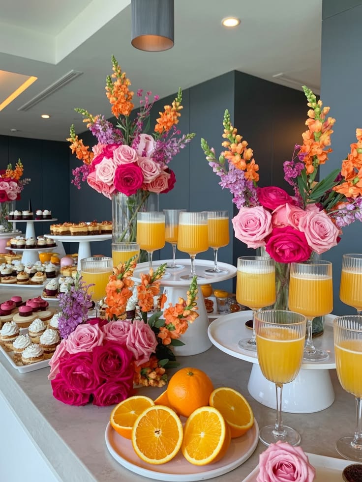 A brunch table with pink florals, oranges, and mimosas